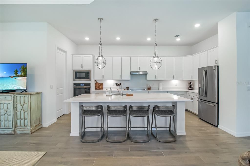 17335 Jadestone Court Venice, FL 34293 - Photo 25 of 54 a kitchen with stainless steel appliances granite countertop a table chairs sink refrigerator and microwave