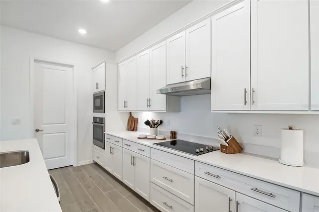 a kitchen with granite countertop white cabinets and stainless steel appliances