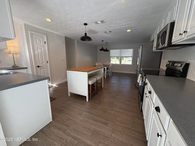 a kitchen with granite countertop a sink a counter top space and cabinets