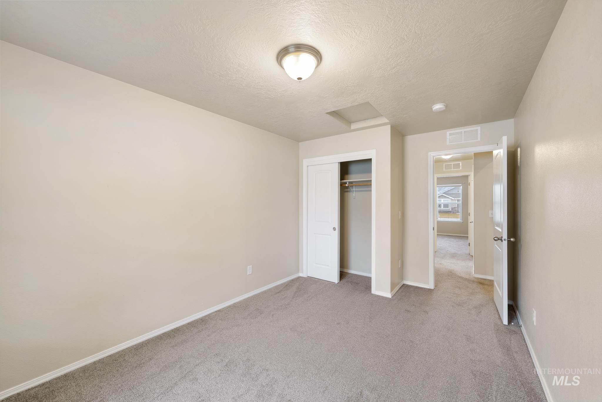 19081 Harley Way Caldwell, ID 83605 - Photo 18 of 35 Unfurnished bedroom featuring a textured ceiling, light colored carpet, a closet, and attic access
