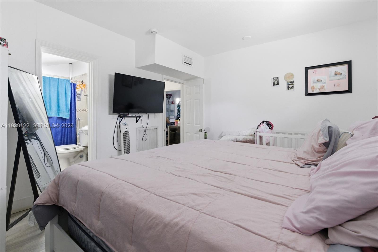 2142 Northwest 33rd Street Miami, FL 33142 - Photo 14 of 26 a bedroom with a bed and a flat tv screen on wall