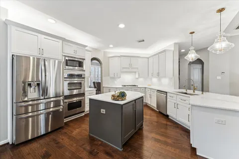 a kitchen with stainless steel appliances granite countertop a sink a stove and a refrigerator