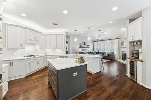 a large kitchen with kitchen island a sink a stove a dining table and chairs with wooden floor