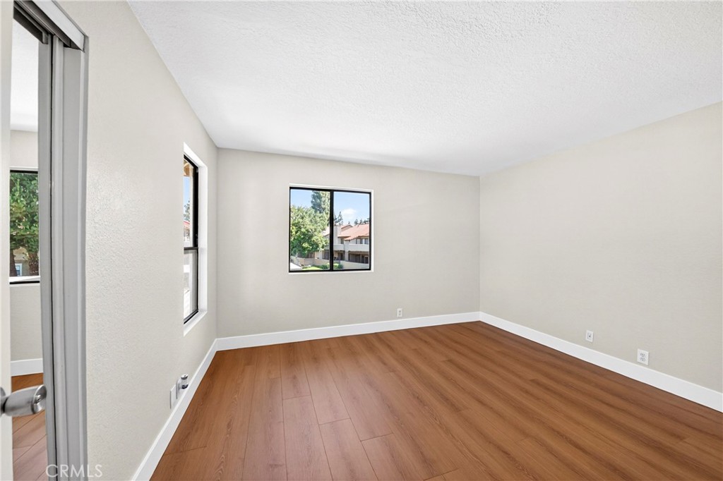 10151 Arrow Route, Unit 26 Rancho Cucamonga, CA 91730 - Photo 15 of 35 an empty room with wooden floor and windows