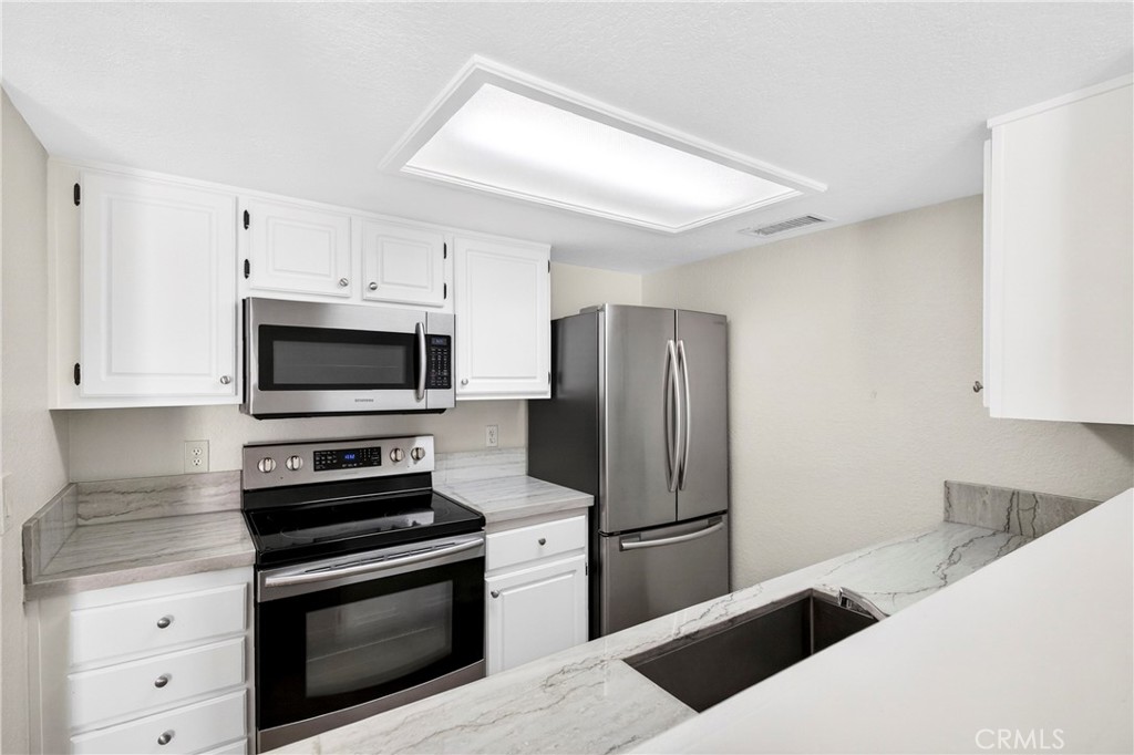 10151 Arrow Route, Unit 26 Rancho Cucamonga, CA 91730 - Photo 3 of 35 a kitchen with stainless steel appliances a refrigerator stove and white cabinets