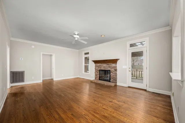 a view of an empty room with a window and wooden floor