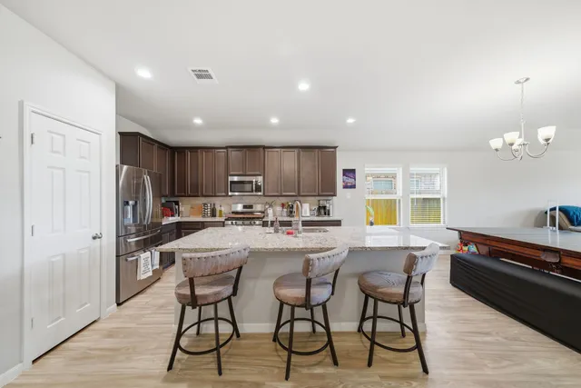 a kitchen with a dining table chairs and refrigerator
