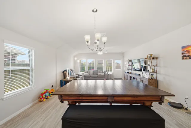 a living room with dining table and a chandelier