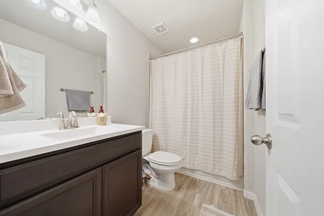 a bathroom with a sink a toilet a mirror and shower curtain