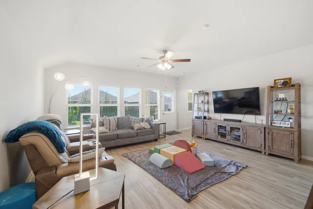 a living room with furniture a flat screen tv and a large window