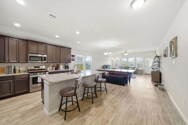 a kitchen with stainless steel appliances a stove a sink a refrigerator white cabinets and wooden floor