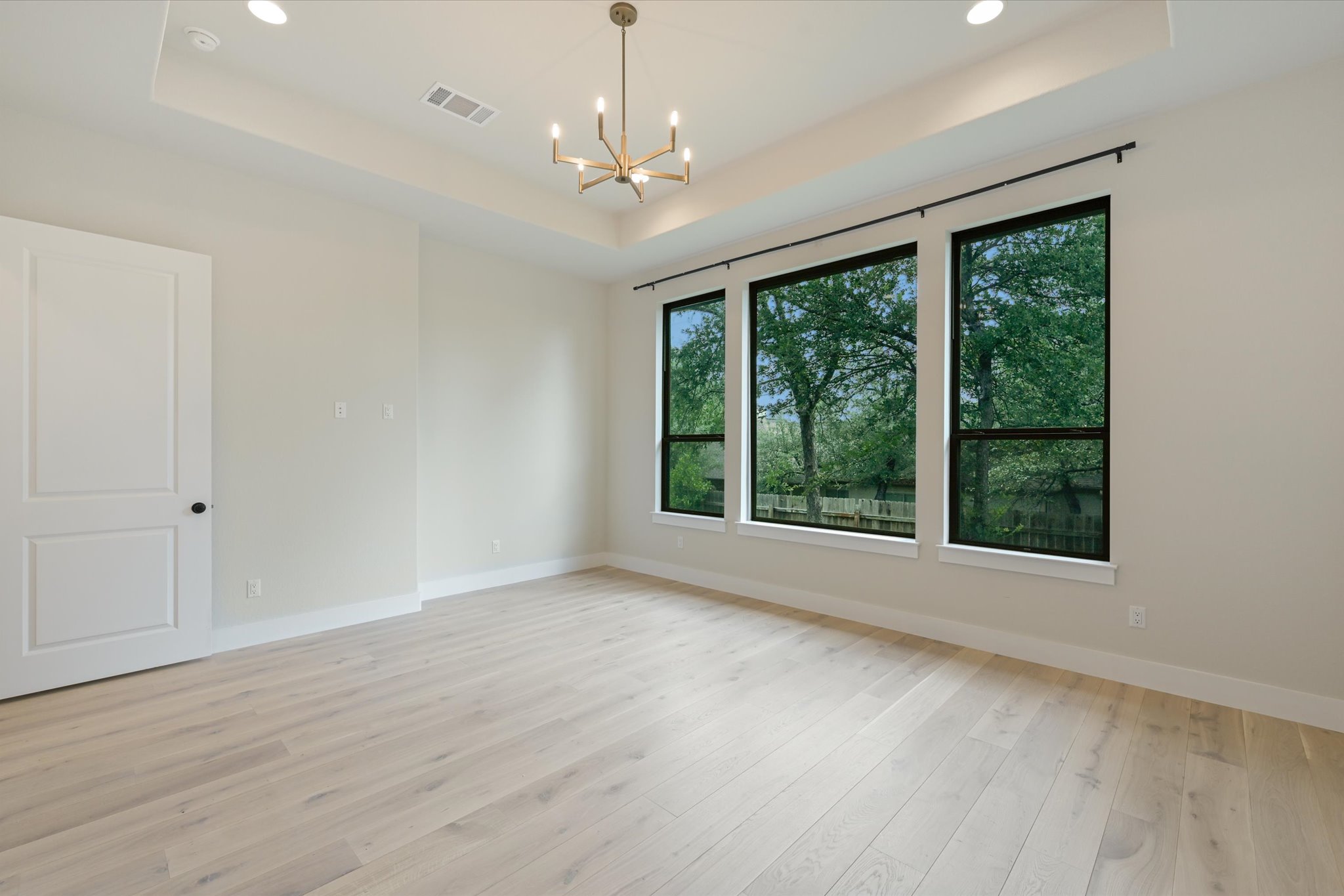 913 Presa Arriba Road Austin, TX 78733 - Photo 17 of 30 Blonde wood flooring and tray ceilings enhance this spacious living area with abundant natural light.
