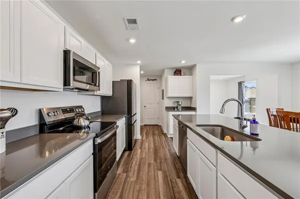 a kitchen with stainless steel appliances granite countertop a stove top oven a sink dishwasher and a refrigerator with wooden cabinets