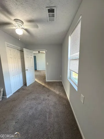 en empty room with windows and chandelier fan
