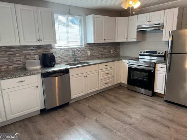a kitchen with stainless steel appliances granite countertop a stove a sink and white cabinets