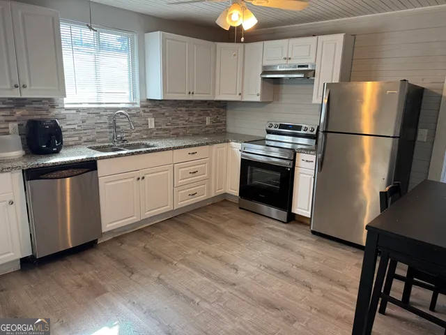 a kitchen with stainless steel appliances granite countertop a refrigerator sink and stove