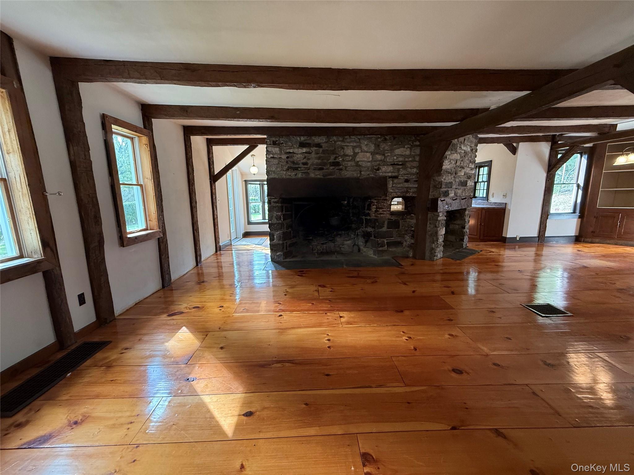 241 White Bridge Road Middletown, NY 10940 - Photo 12 of 29 Unfurnished living room with hardwood / wood-style floors, a stone fireplace, healthy amount of natural light, and beamed ceiling