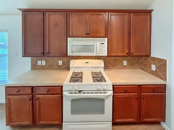 a kitchen with granite countertop a stove a sink and a microwave