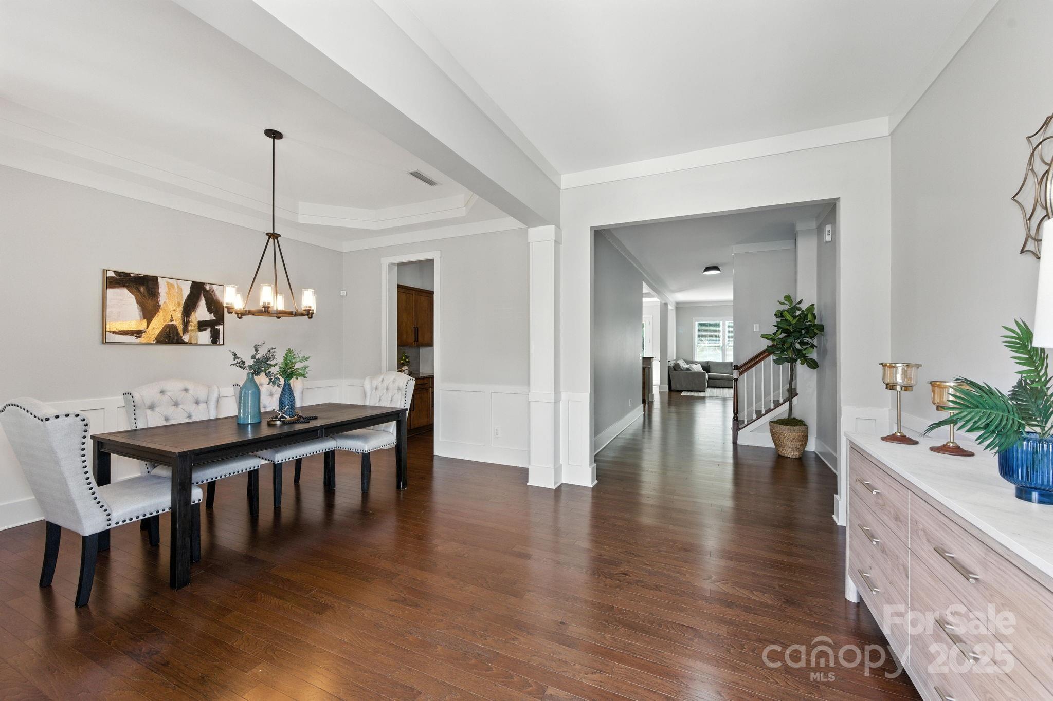 3076 Amaranth Drive Tega Cay, SC 29708 - Photo 5 of 39 a dining room with furniture wooden floor a rug a potted plant and a chandelier
