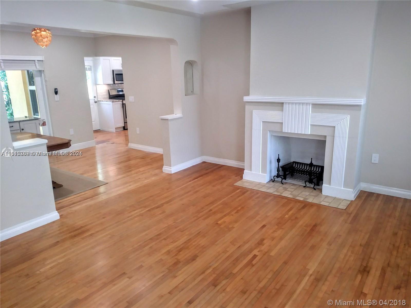 a view of a livingroom with wooden floor and a fireplace