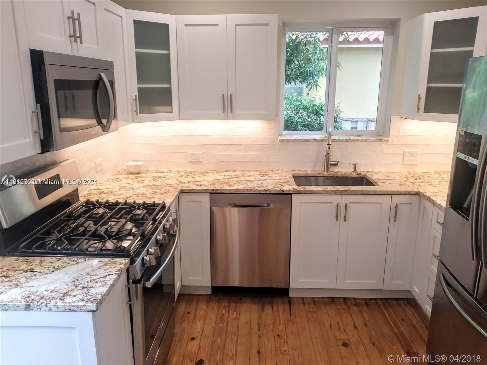 610 Southwest 25th Road Miami, FL 33129 - Photo 12 of 30 a kitchen with granite countertop a stove a sink dishwasher and wooden cabinets with wooden floor