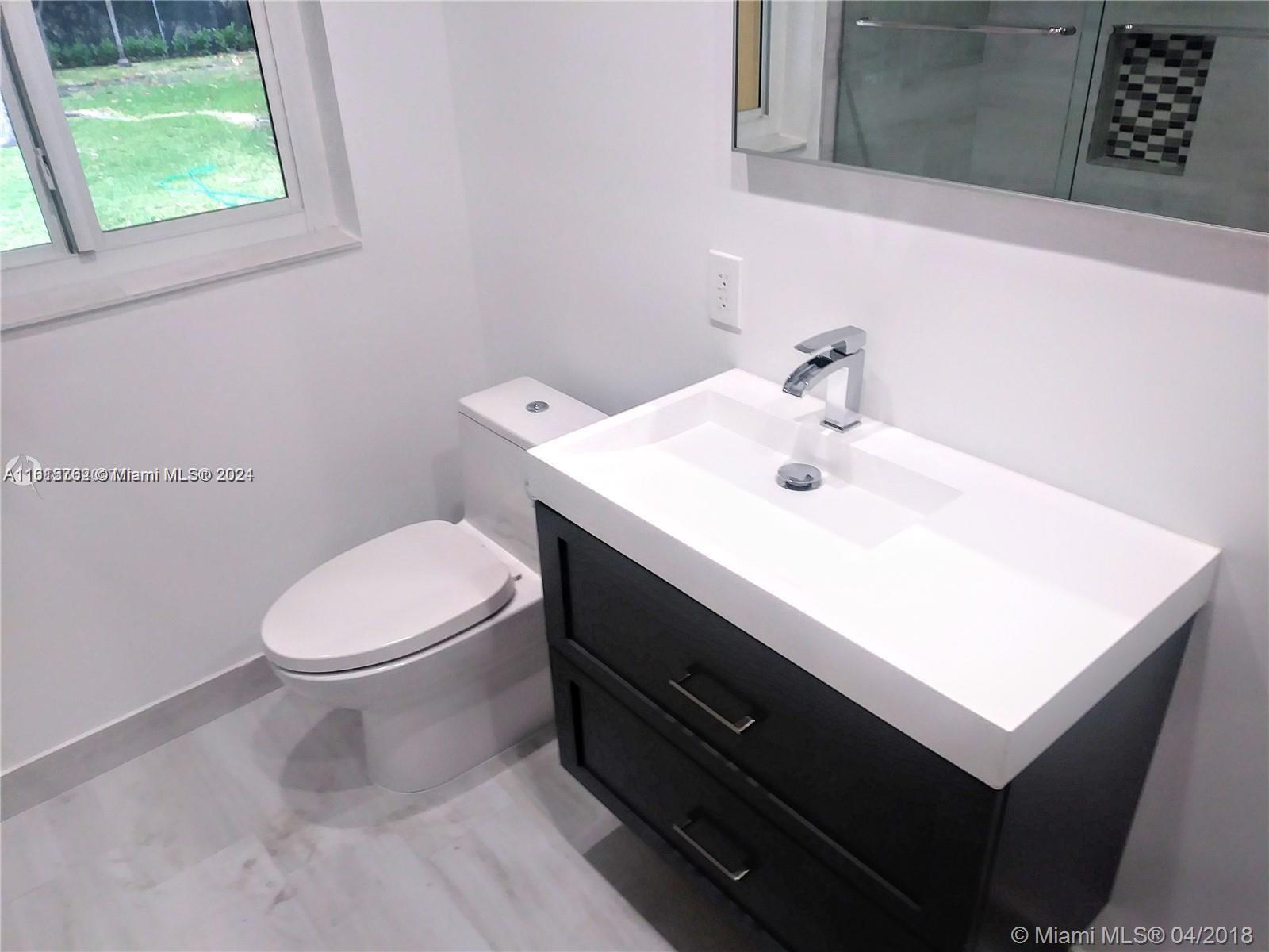 610 Southwest 25th Road Miami, FL 33129 - Photo 17 of 30 a bathroom with a sink a mirror and a toilet