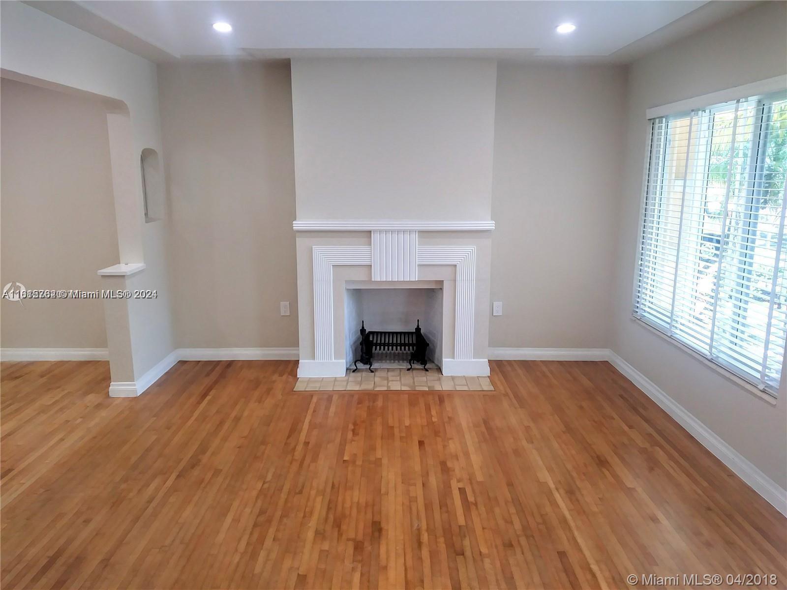 610 Southwest 25th Road Miami, FL 33129 - Photo 4 of 30 an empty room with wooden floor fireplace and windows