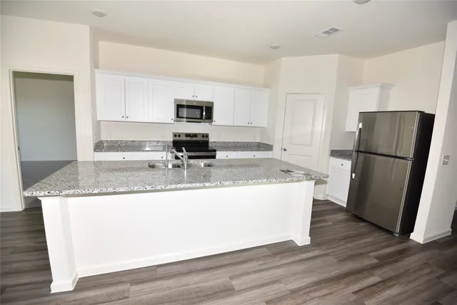 a kitchen with granite countertop a refrigerator and a stove top oven