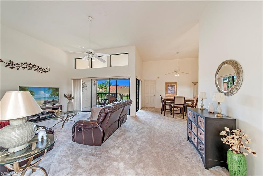 643 Beachwalk Circle, Unit D202 Naples, FL 34108 - Photo 12 of 22 a living room with furniture a rug and a chandelier