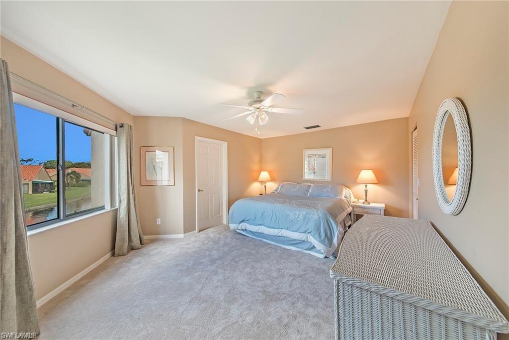 643 Beachwalk Circle, Unit D202 Naples, FL 34108 - Photo 15 of 22 a bedroom with a large bed and a chandelier