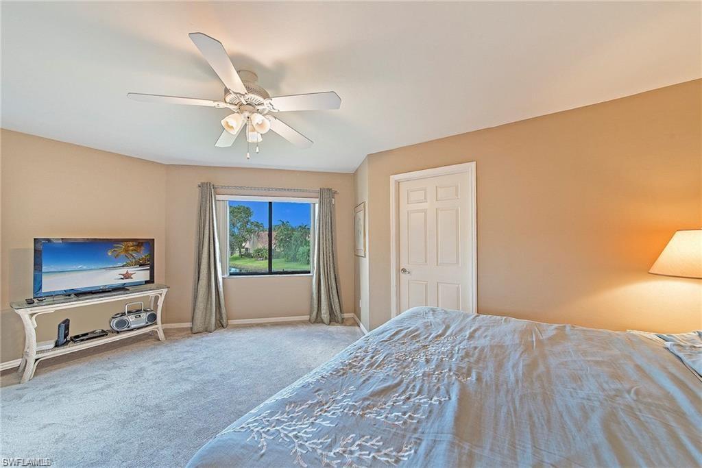 643 Beachwalk Circle, Unit D202 Naples, FL 34108 - Photo 17 of 22 a bedroom with a bed and a chandelier