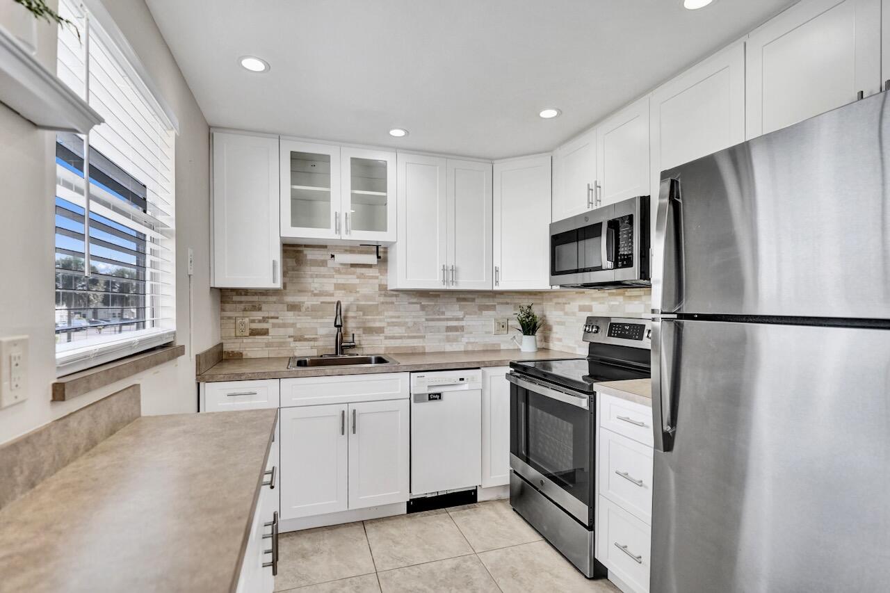 505 Monaco Way Delray Beach, FL 33446 - Photo 18 of 58 a kitchen with stainless steel appliances granite countertop a stove a sink and a refrigerator