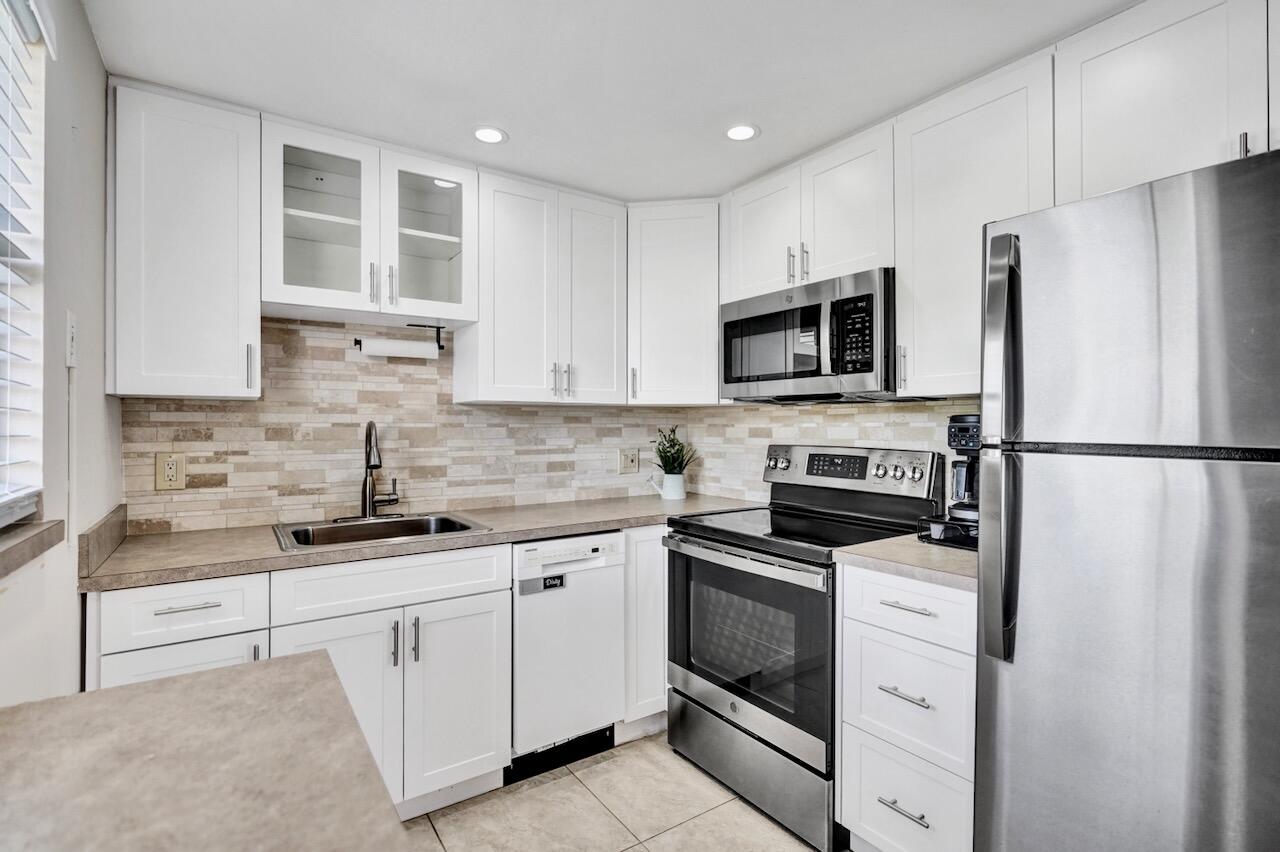 505 Monaco Way Delray Beach, FL 33446 - Photo 19 of 58 a kitchen with cabinets stainless steel appliances and a sink