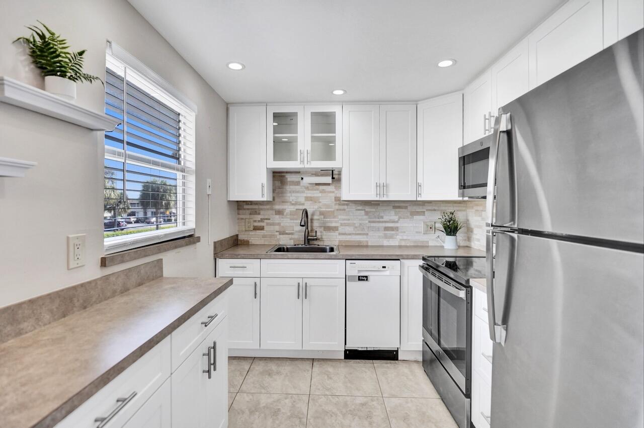 505 Monaco Way Delray Beach, FL 33446 - Photo 20 of 58 a kitchen with a refrigerator sink and cabinets