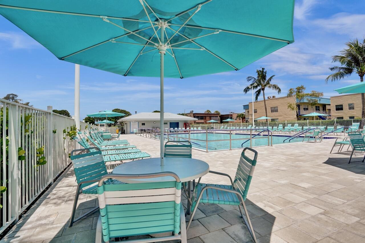 505 Monaco Way Delray Beach, FL 33446 - Photo 51 of 58 a patio with a table and chairs under an umbrella
