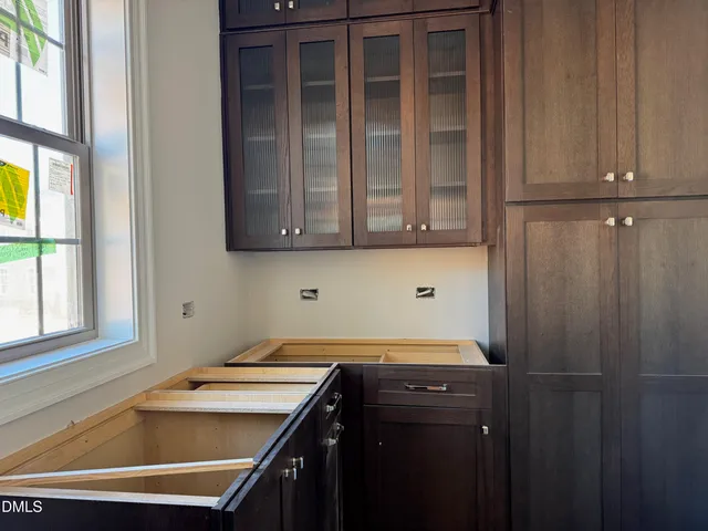 a view of an empty room with kitchen and window