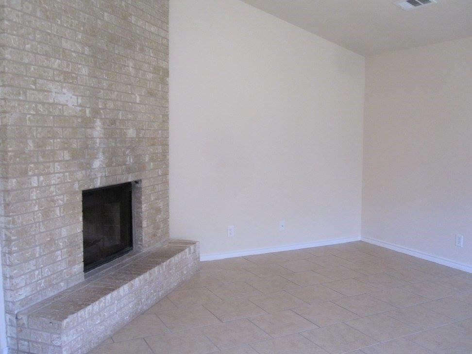 8811 Clearbrook Trail Austin, TX 78729 - Photo 10 of 38 lft A - A well-appointed living room features a brick fireplace with a hearth and durable tile flooring.