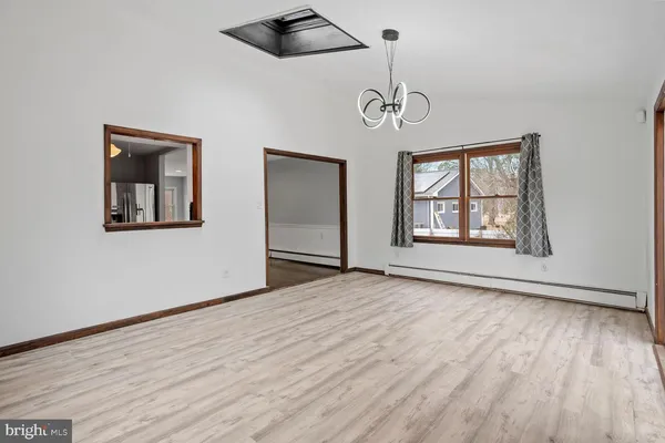 a view of an empty room with wooden floor and windows