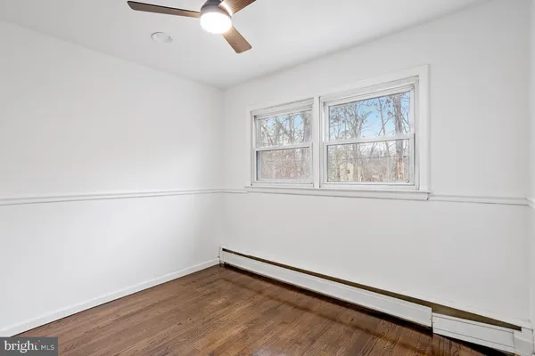 an empty room with wooden floor fan and windows