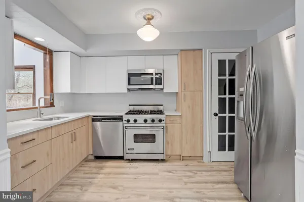 a kitchen with cabinets stainless steel appliances and a window