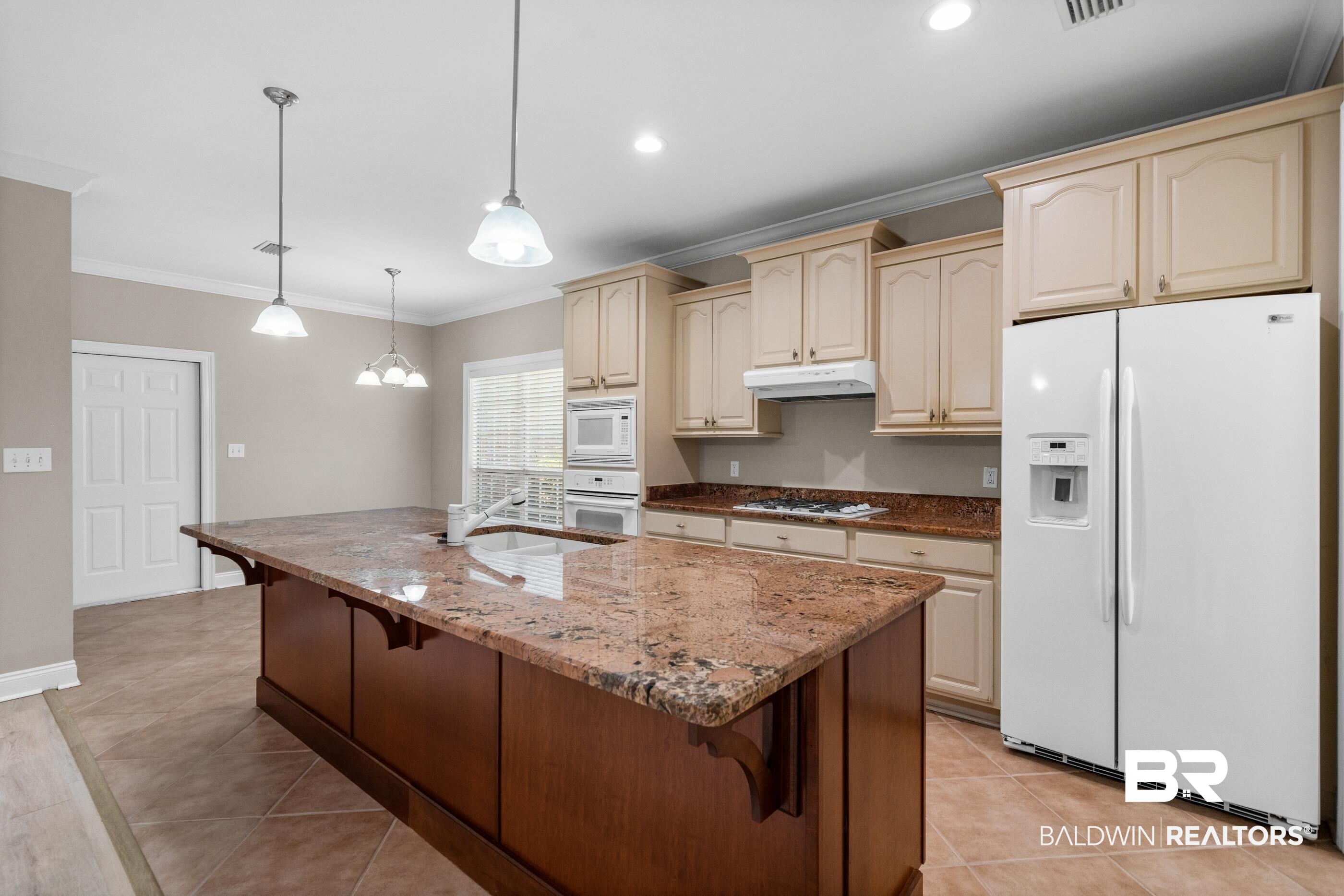 303 Savannah Circle Foley, AL 36535 - Photo 11 of 34 Kitchen featuring a large island with a stone countertop, wood-finish cabinetry, and recessed lighting