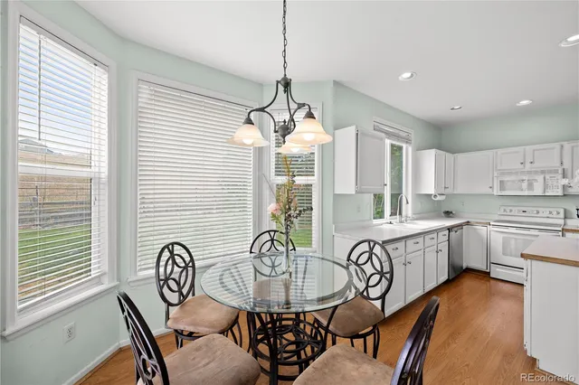 a very nice looking kitchen with granite countertop a stove a sink a dining table and chairs