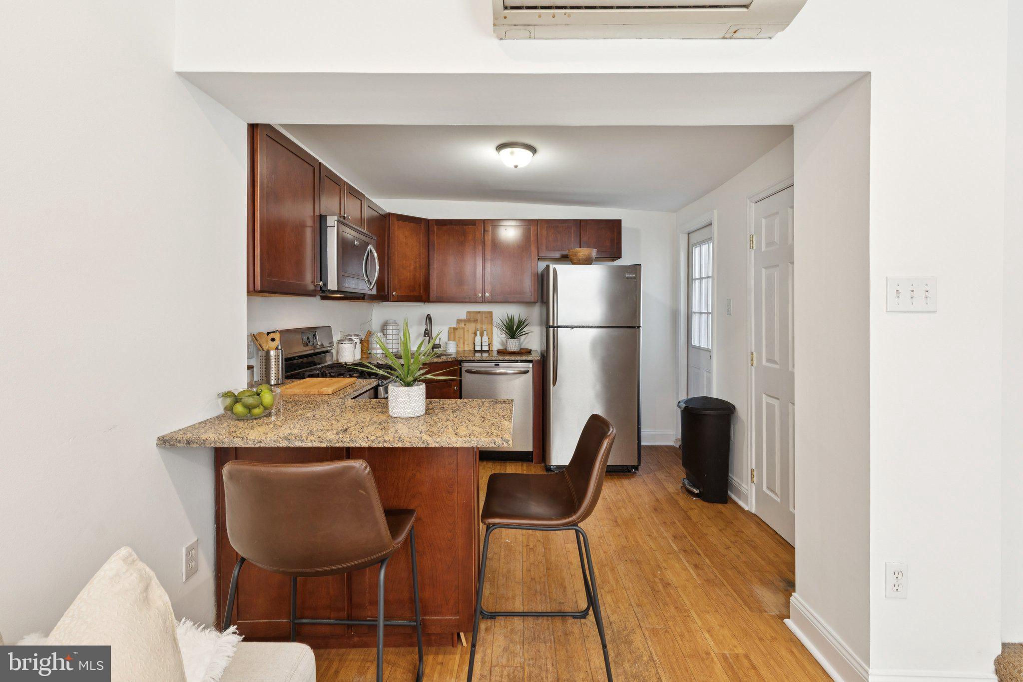 525 Fitzwater Street, Unit 4 Philadelphia, PA 19147 - Photo 7 of 20 a kitchen with stainless steel appliances granite countertop a dining table chairs refrigerator and sink