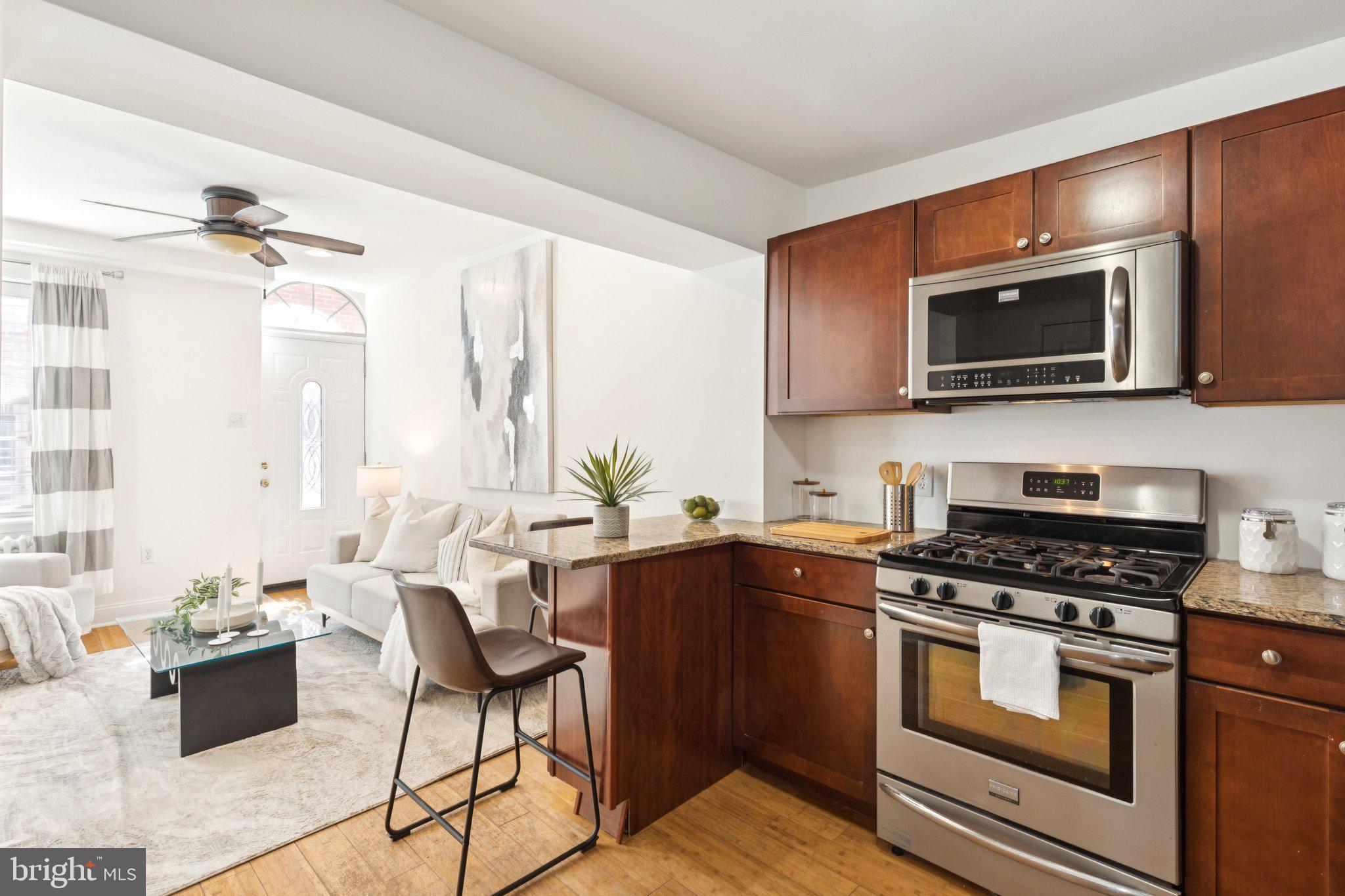 525 Fitzwater Street, Unit 4 Philadelphia, PA 19147 - Photo 9 of 20 a kitchen with stainless steel appliances kitchen island granite countertop a stove top oven a sink dishwasher a dining table and chairs with wooden floor