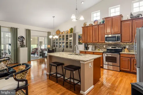 a kitchen with granite countertop a stove a sink dishwasher and a refrigerator with wooden floor