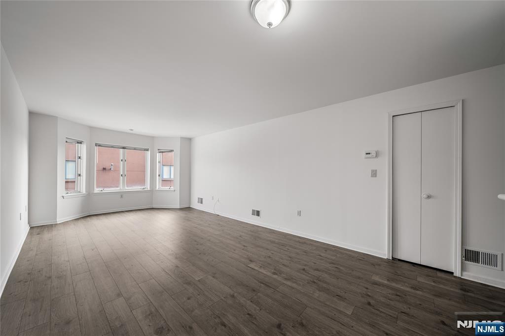 402 Chase Court, Unit 402 Edgewater, NJ 07020 - Photo 7 of 21 a view of an empty room with wooden floor and window