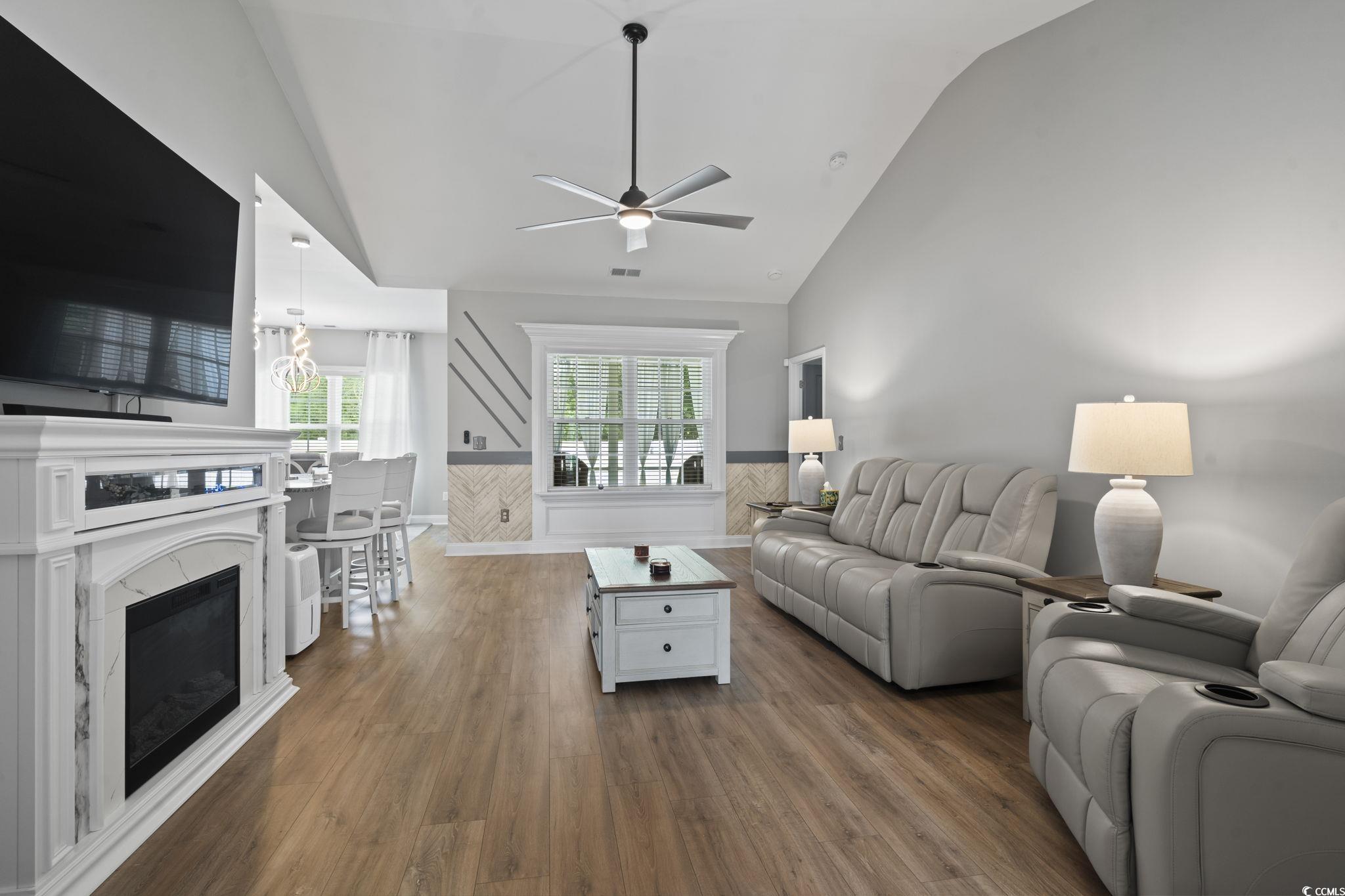 804 Twickenham Loop Longs, SC 29568 - Photo 7 of 26 Living area with a wainscoted wall, dark wood-style floors, high vaulted ceiling, a fireplace, and a ceiling fan