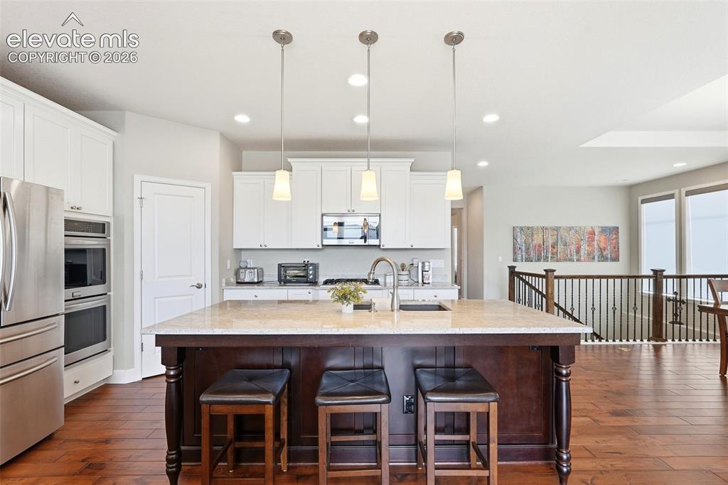 1394 Promontory Bluff View Colorado Springs, CO 80921 - Photo 12 of 47 a large kitchen with granite countertop a dining table chairs stainless steel appliances and cabinets