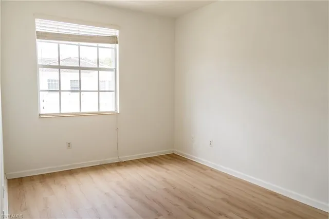 an empty room with wooden floor and window