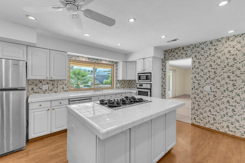 74075 Setting Sun Trail Palm Desert, CA 92260 - Photo 17 of 52 a kitchen with stainless steel appliances a stove a sink dishwasher and a refrigerator with wooden floor